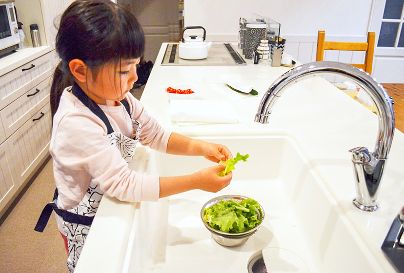 台所で野菜を洗う女の子の写真
