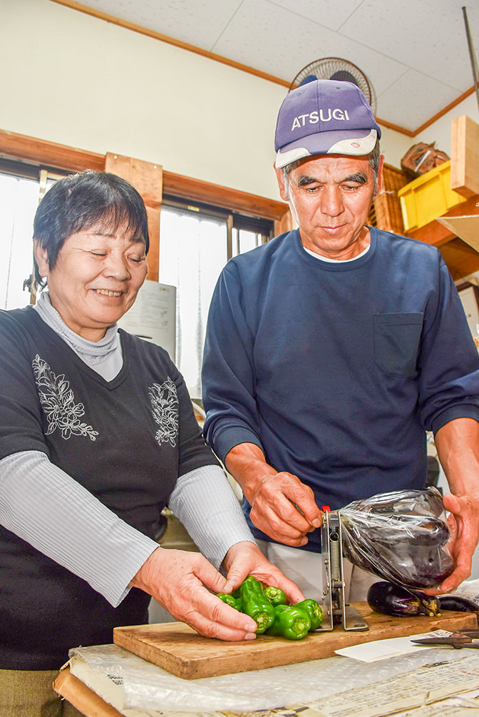 夫婦で野菜の袋詰めを行っているの写真