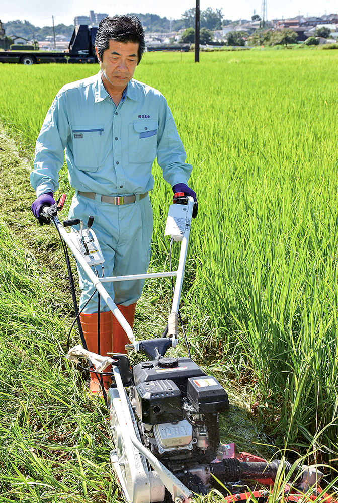 専用の草刈り機で畦畔を除草の写真