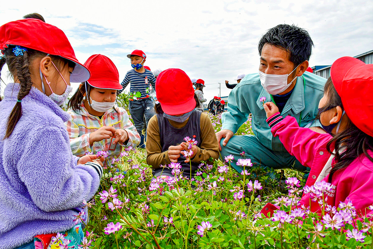 JA職員とともにレンゲ摘みを楽しむ児童の写真