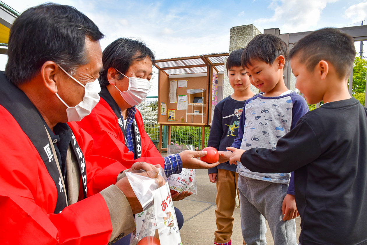 子どもたちに厚木トマトの特徴を説明する部会員の写真