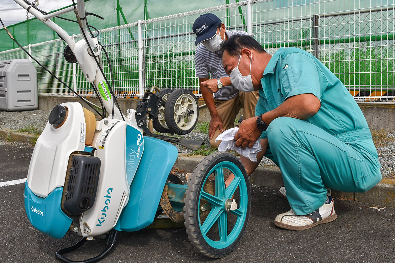 生産者とともに農業機械の点検作業を行うJA職員の写真