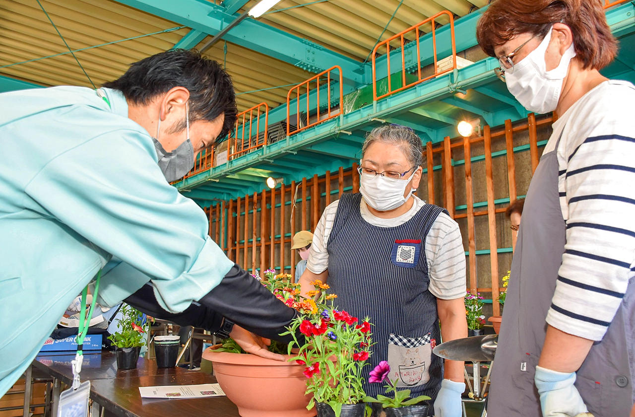 JA職員から寄せ植えのポイントを学ぶ参加者の写真