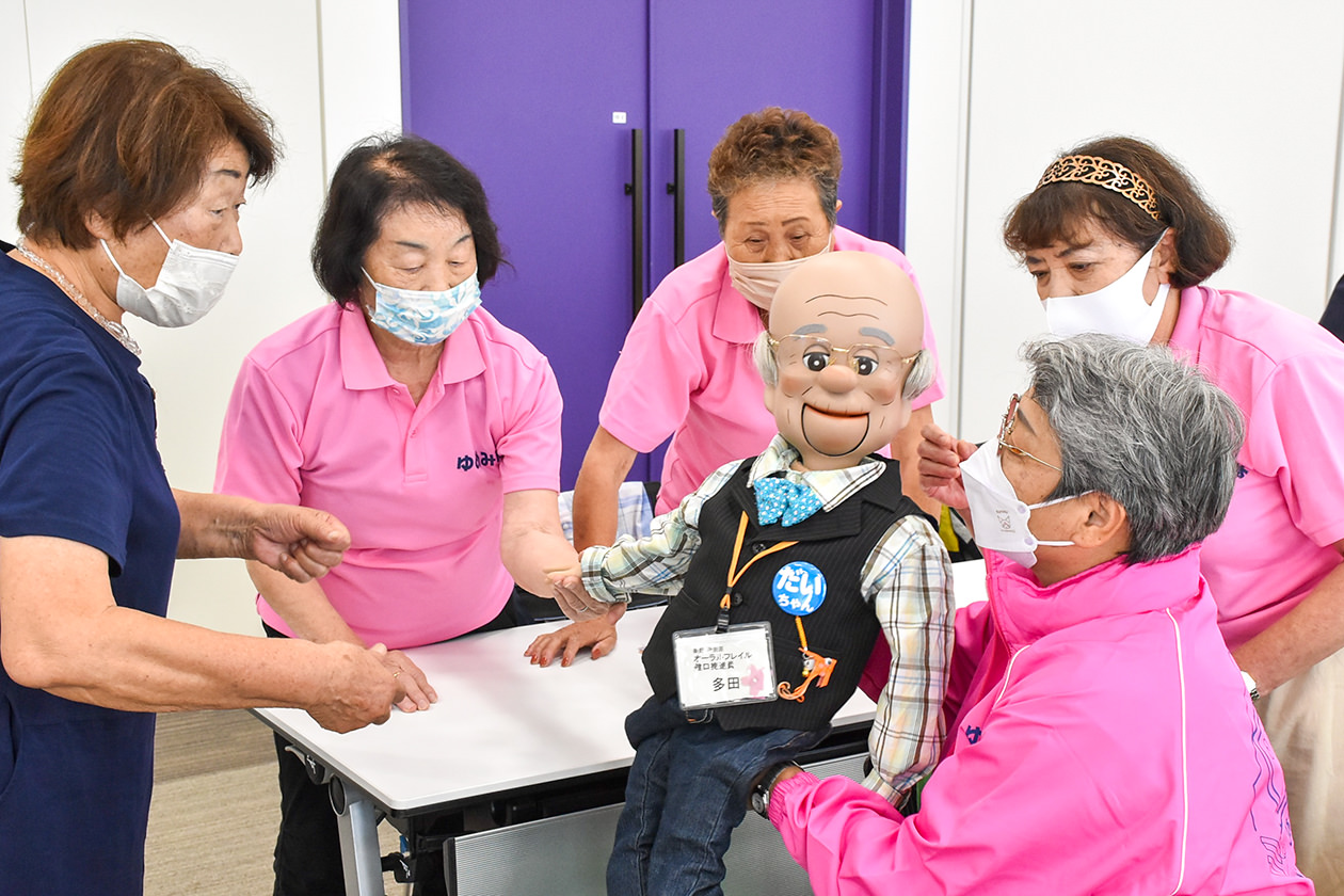 講師（左）から腹話術を学ぶ隊員らの写真