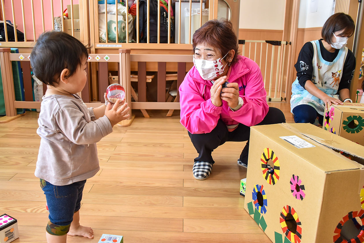 隊員と共に手作りおもちゃで遊ぶ園児の写真