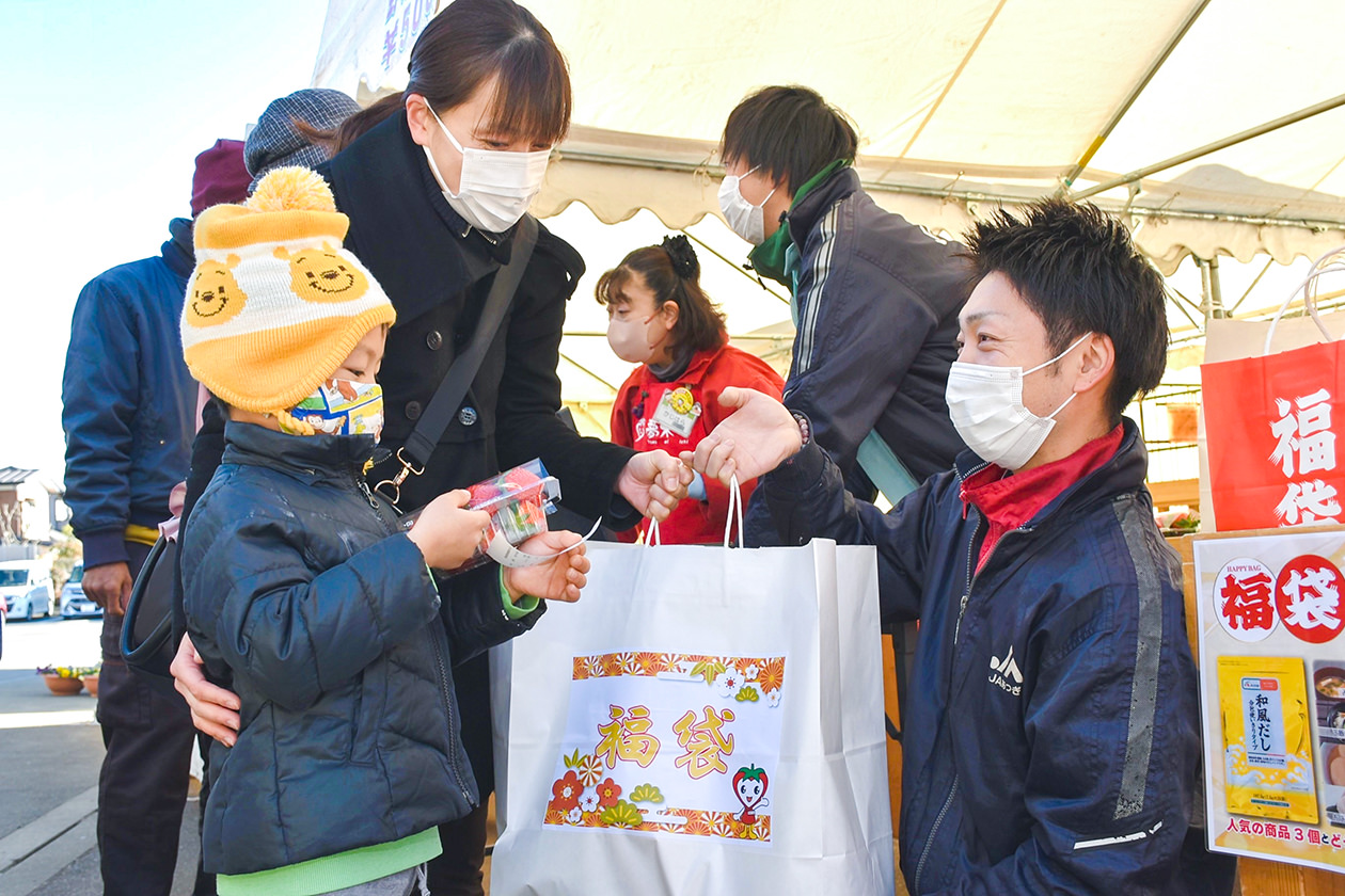 野菜の福袋を手渡すJA職員の写真