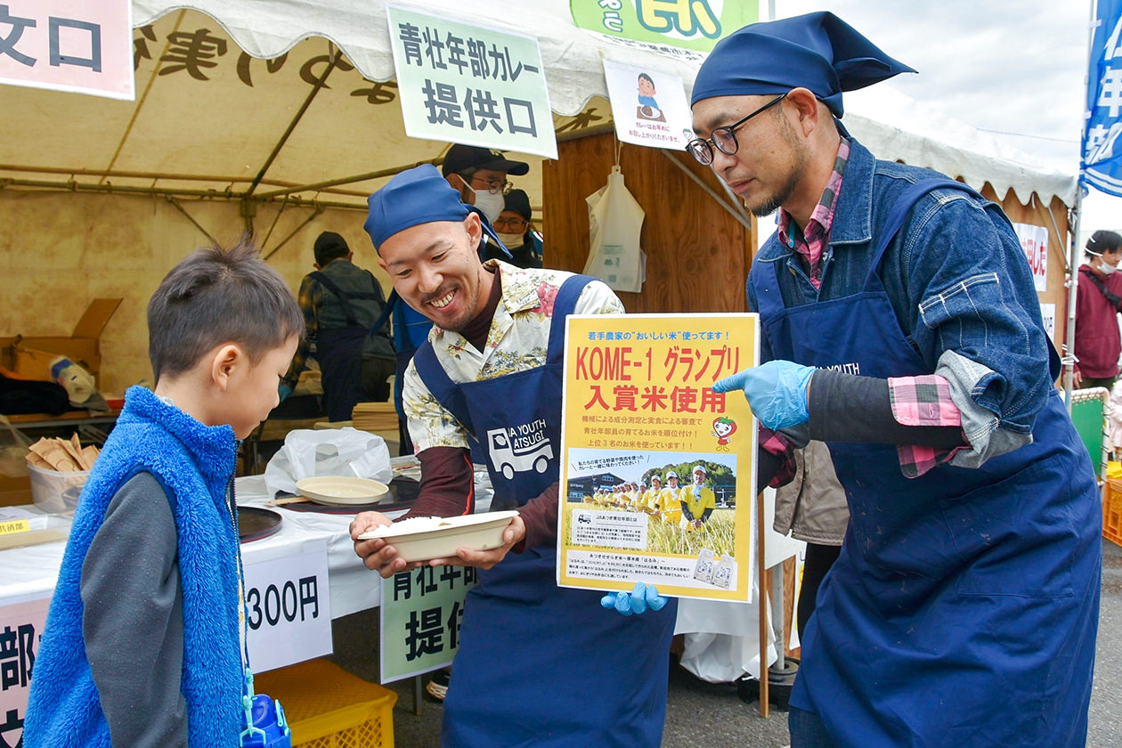 農業まつりで厚木産米のおいしさを伝える鈴木部長（右）の写真
