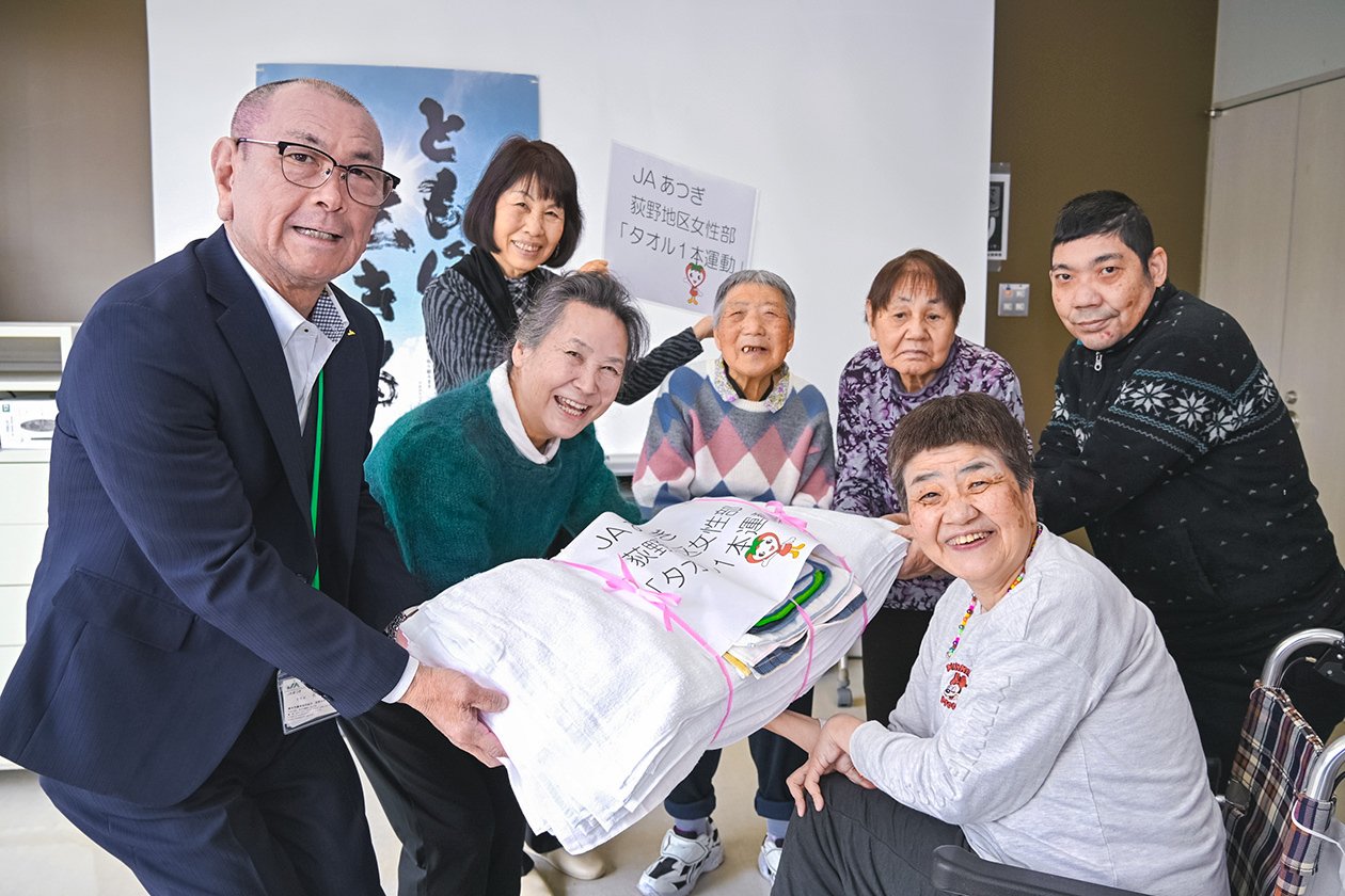 利用者にタオルを手渡す部代表者とJA職員の写真