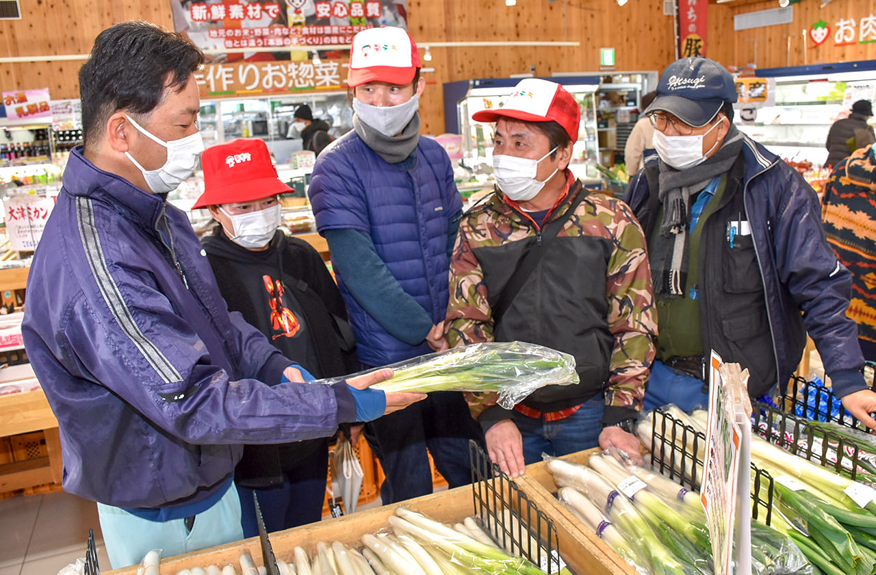 JA職員とともに出荷時の注意点を確認する修了生の写真