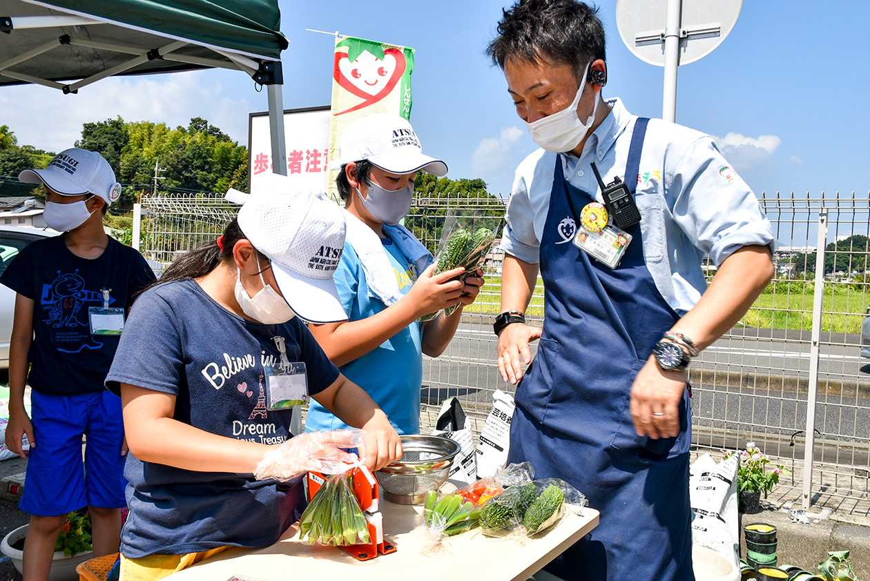 店長から野菜の袋詰め作業を教わるスクール生の写真