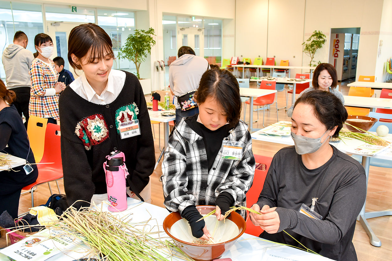 協力して脱穀作業を行う参加者親子の写真