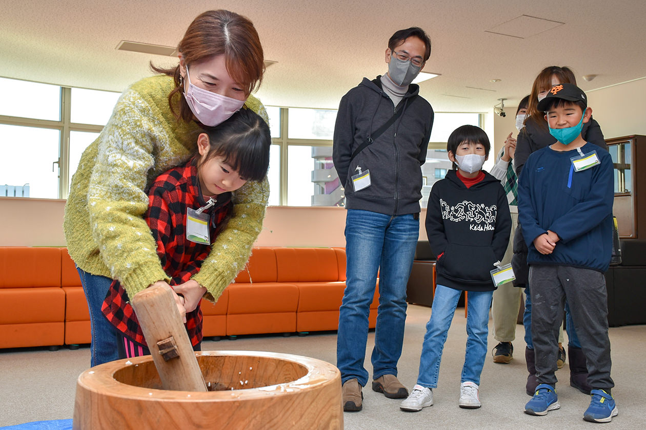 餅つきを体験する参加者親子の写真